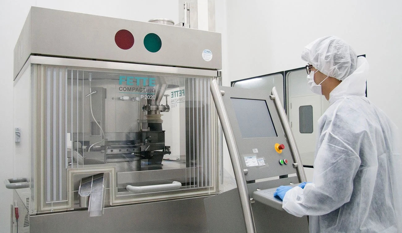 Operator in protective clothing working with production equipment in Vita Green’s manufacturing facility